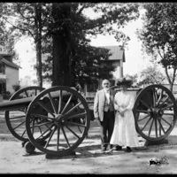 Mabel Wohlbruck and man standing beside a large cannon